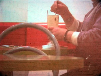 hands with takeaway drink, sitting. It's grainy and red